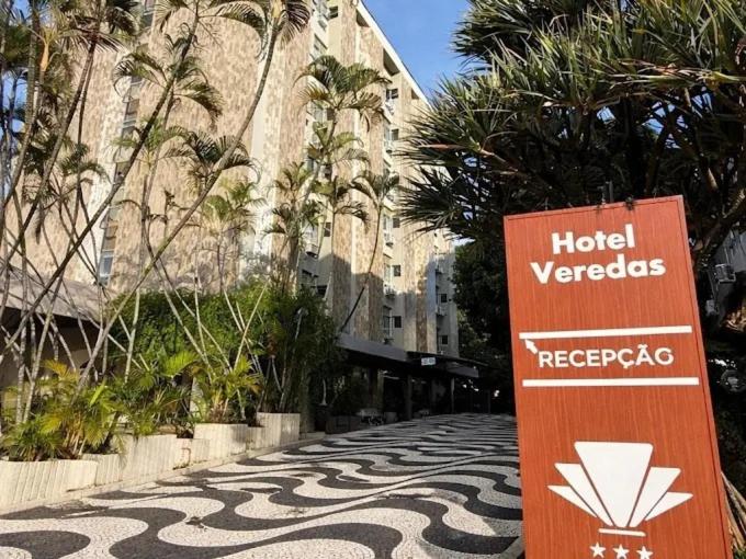 a sign on the side of a road with palm trees at Hotel Veredas in Paracatu