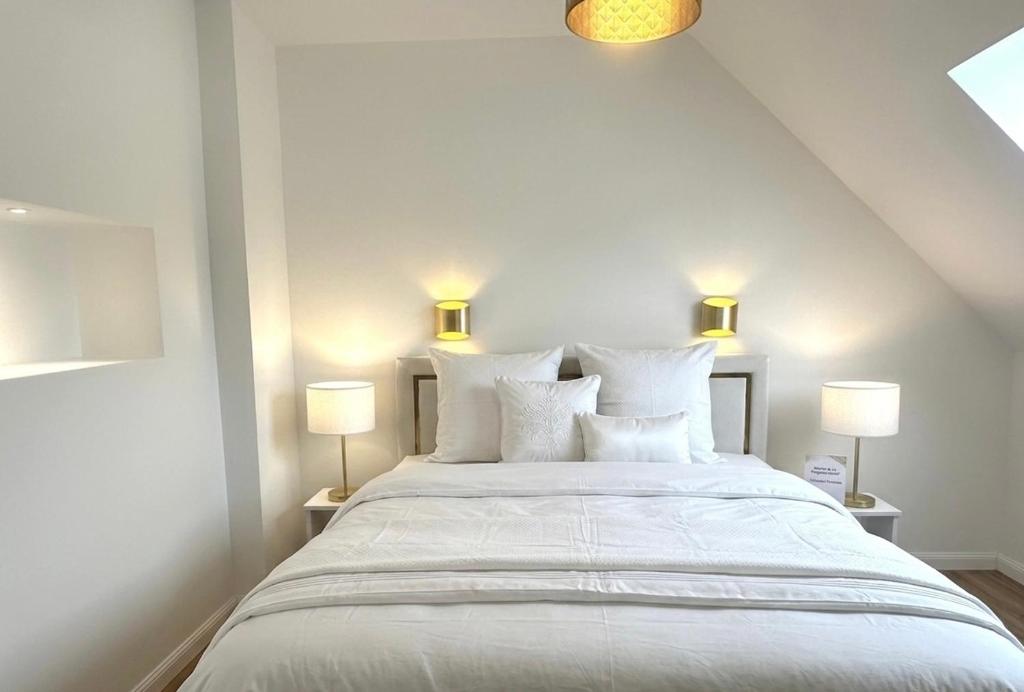 a bedroom with a large white bed with two lamps at Bel appartement sous combles in Argelès-Gazost