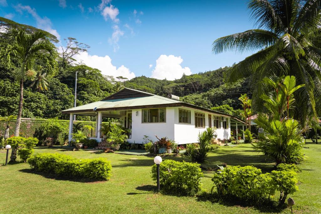 a white house with a palm tree in a yard at Fare Faaroa Lodge in Taputapuapea