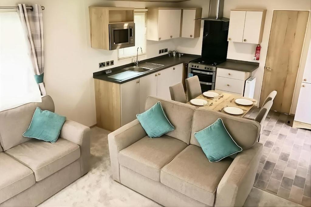 a living room with two couches and a kitchen at Spacious Caravan - Durdle Door Holiday Park in West Lulworth