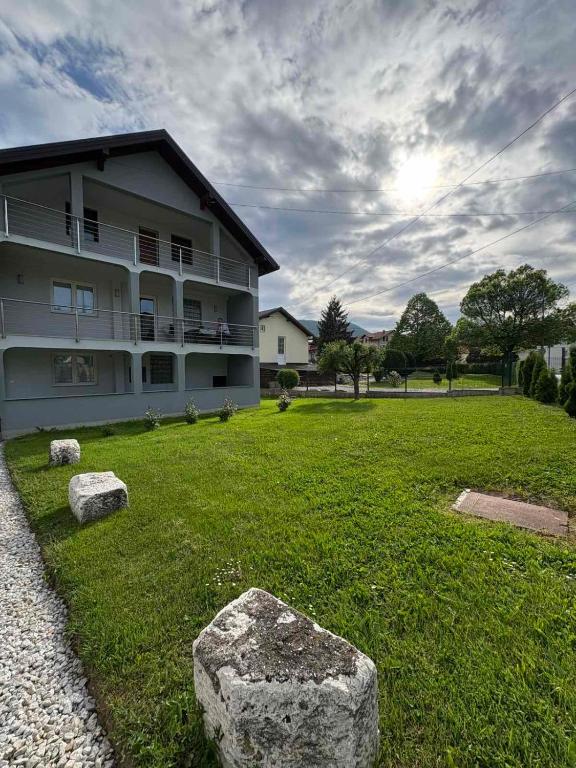 a building with a yard with rocks in the grass at Vila Ziki in Sarajevo