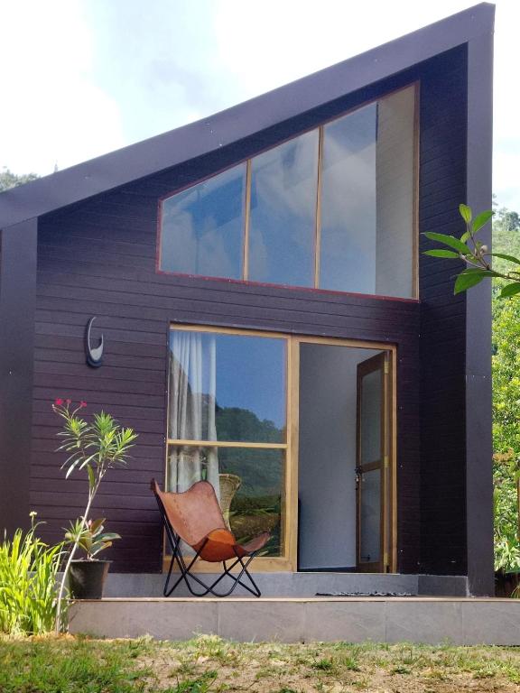 a house with a chair in front of it at Galactic Glow Villa & Resort in Deniyaya