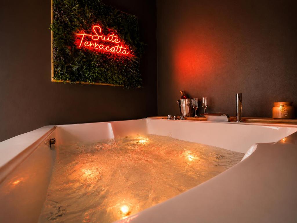 a bath tub filled with water with a neon sign at Evasion Terracotta - Jacuzzi privatif in Saint-Gaudens