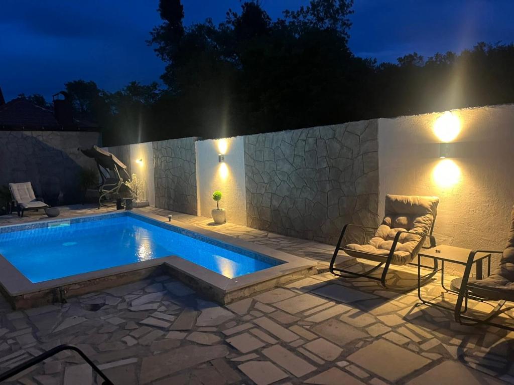 a swimming pool at night with chairs and lights at Apartmani Vukotić in Budva