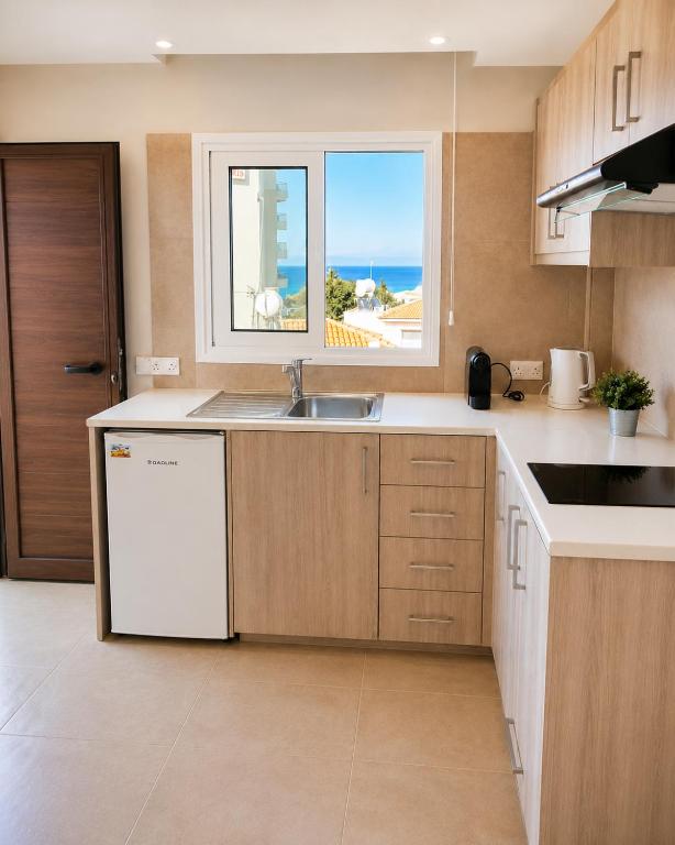 a kitchen with a sink and a window at Proteas Mare Suites in Protaras