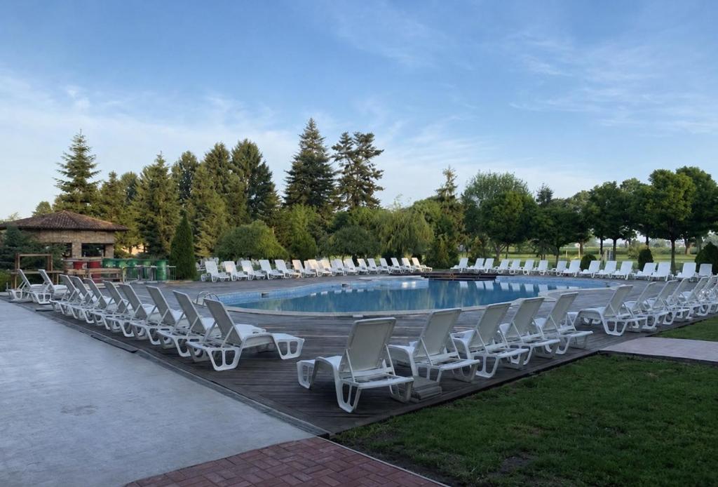 a row of lounge chairs next to a swimming pool at Hipodruma Resort & Pool in Dobrich