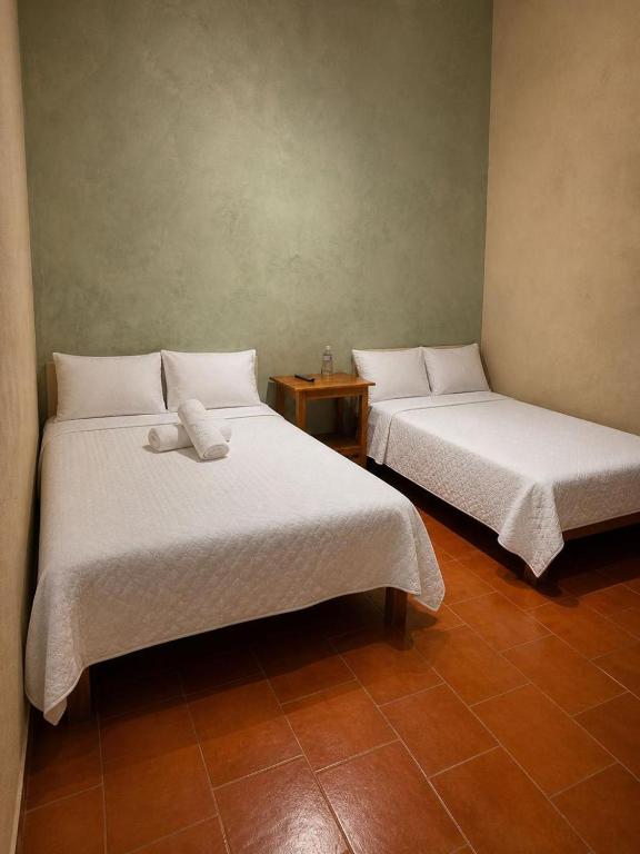 two beds with white sheets in a room at Hotel Mary o in Valle de Bravo