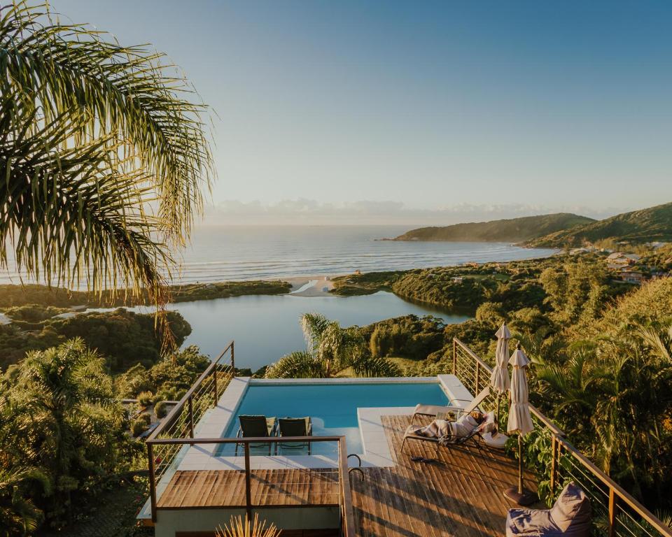 a villa with a pool and a view of the ocean at Villa Gardena Suites in Praia do Rosa