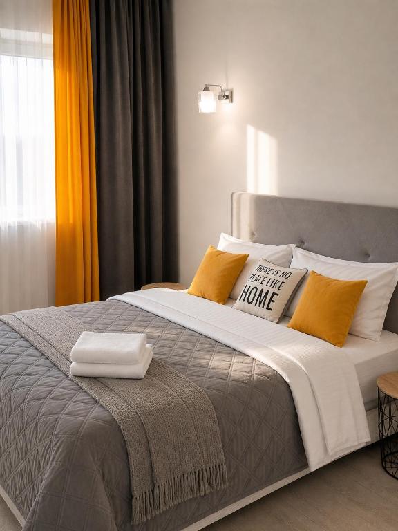 a bedroom with a large bed with yellow and white pillows at Oberig Royal Apartments НОВОБУДОВА, найкращий район, дуже ЧИСТО in Chernivtsi