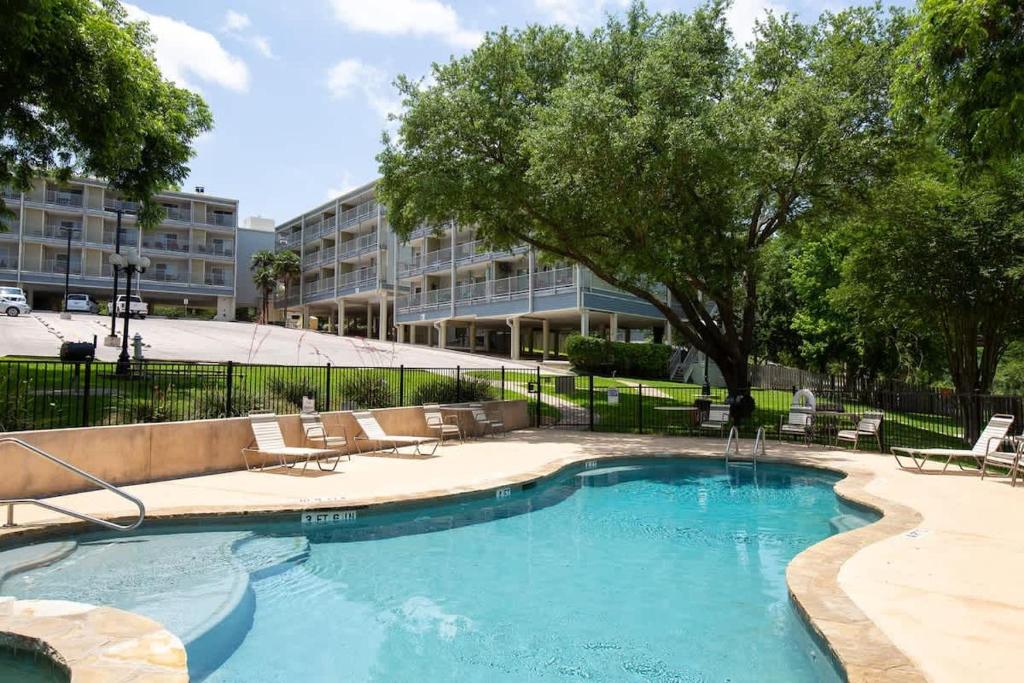a swimming pool with chairs and a building at RRC A302 River Hippie in New Braunfels