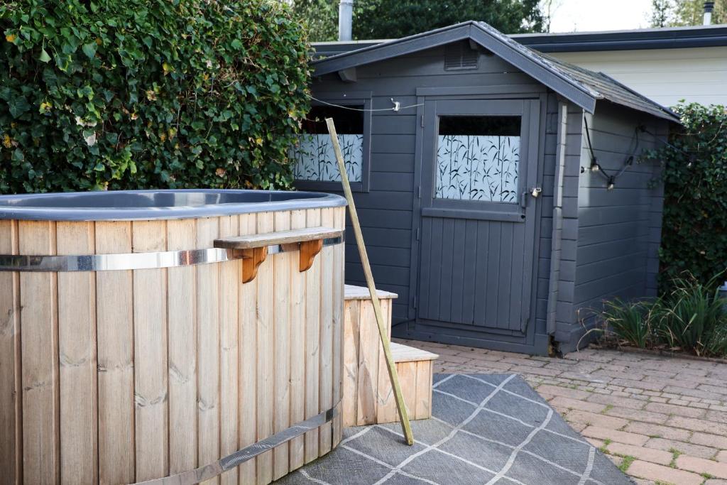 a black shed with a hot tub in front of it at Knus Relaxchalet met Privé Hottub in Voorthuizen