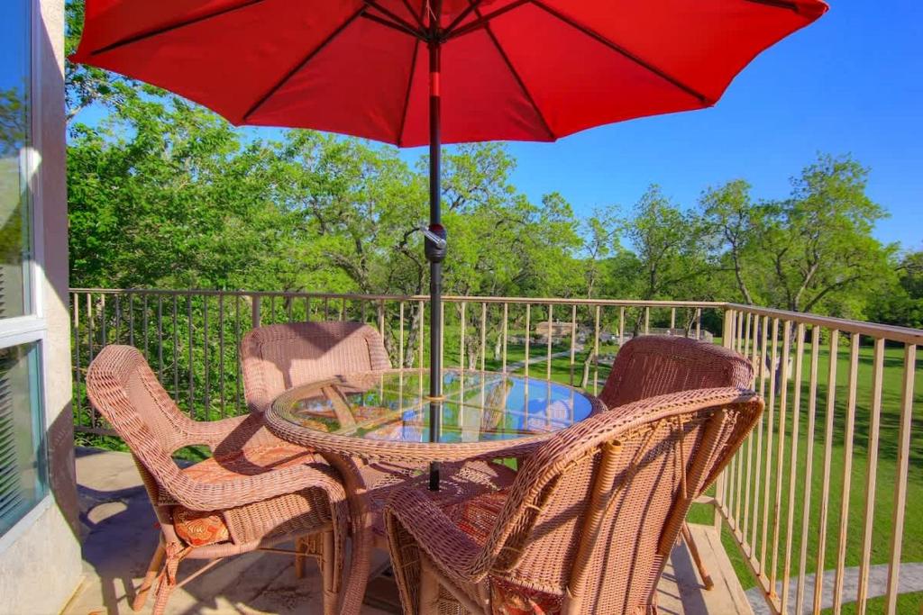a table and chairs with a red umbrella on a porch at WW D302 Chateau Relaxeau in New Braunfels