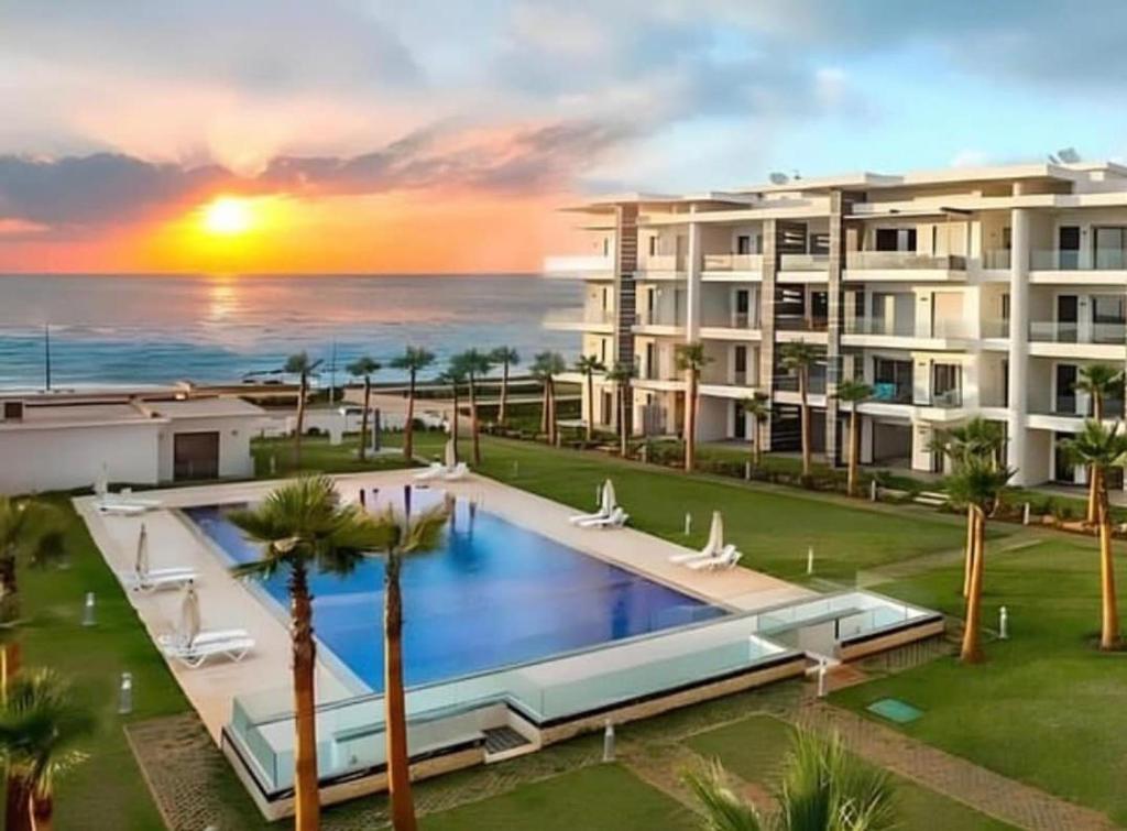 a large apartment building with a swimming pool and the ocean at Beachfront luxury 2 bedroom appartement with pool and gym in Mansouria