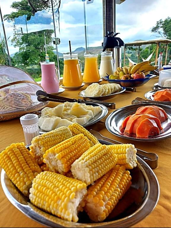 a table topped with plates of corn on the cob at Pousada Mirante dos Ipês - Experiência Rural em Capitólio in Capitólio