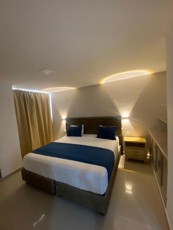 a bedroom with a large bed with blue pillows at Hotel Yivinaca in Barranquilla