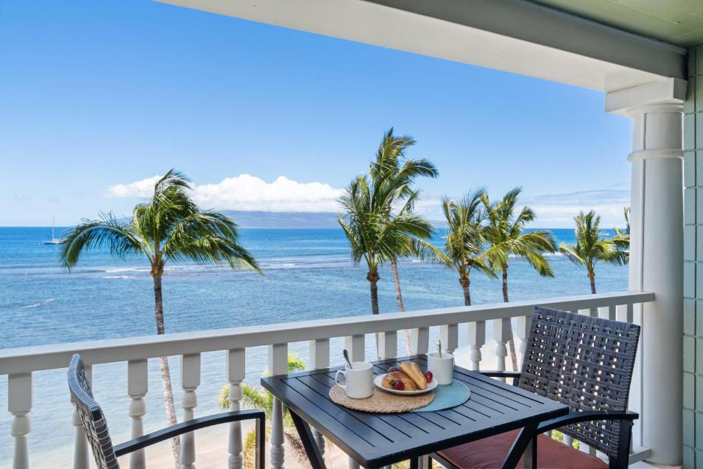 a table with a plate of food on a balcony overlooking the ocean at Lahaina Shores 511 in Lahaina