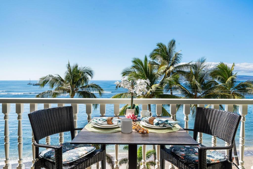 a table with a meal on a balcony with the ocean at Lahaina Shores 515 in Lahaina
