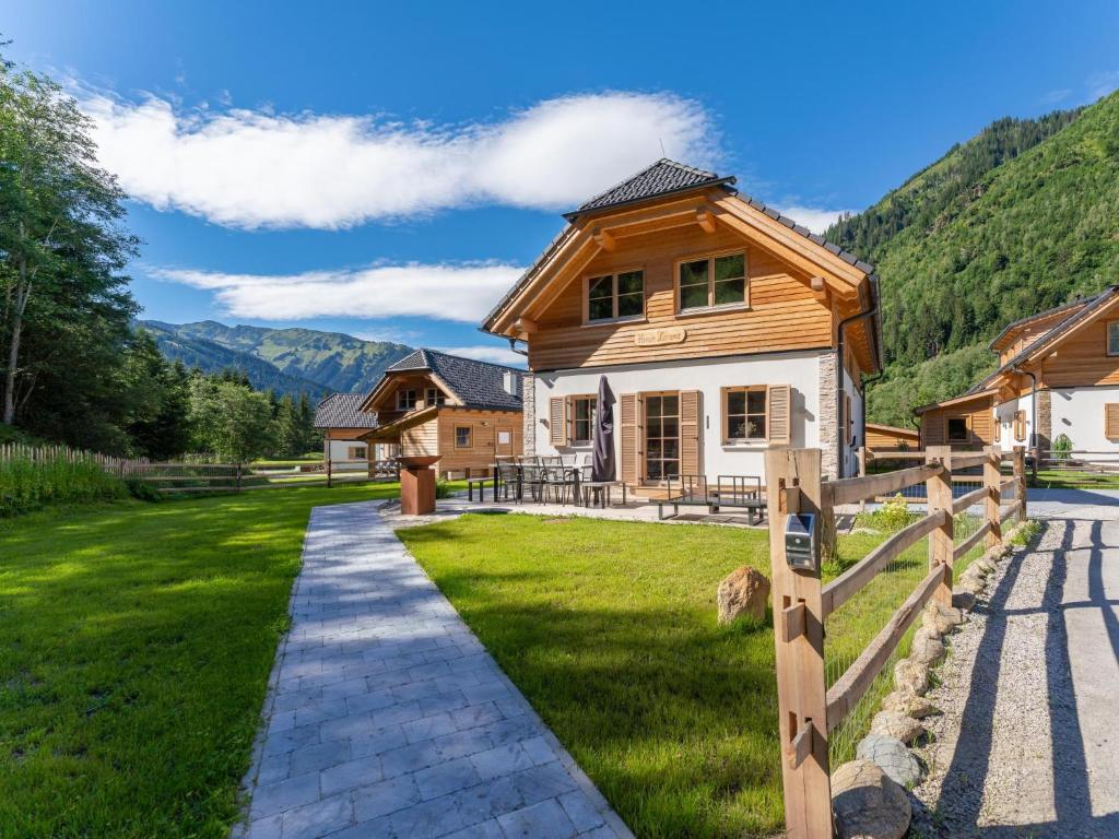 a wooden house with a fence in front of a yard at Haus Laura in Donnersbachwald