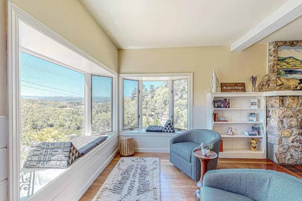a living room with a large window and blue chairs at Dragon Cottage in Healdsburg