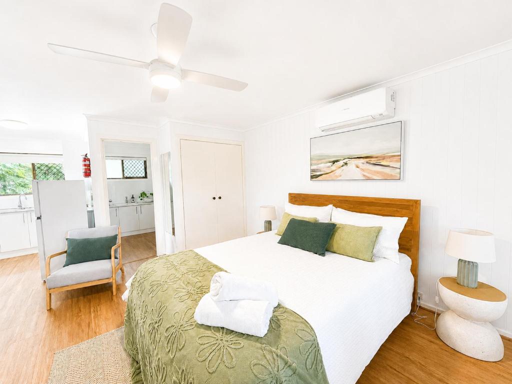 a white bedroom with a bed and a ceiling fan at Hidden Gem at The Bay - Resort Pool - 300m to Beach in Urangan