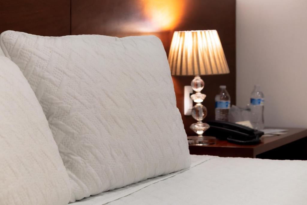 a white pillow sitting on a bed with a lamp at El Navegante in Campeche