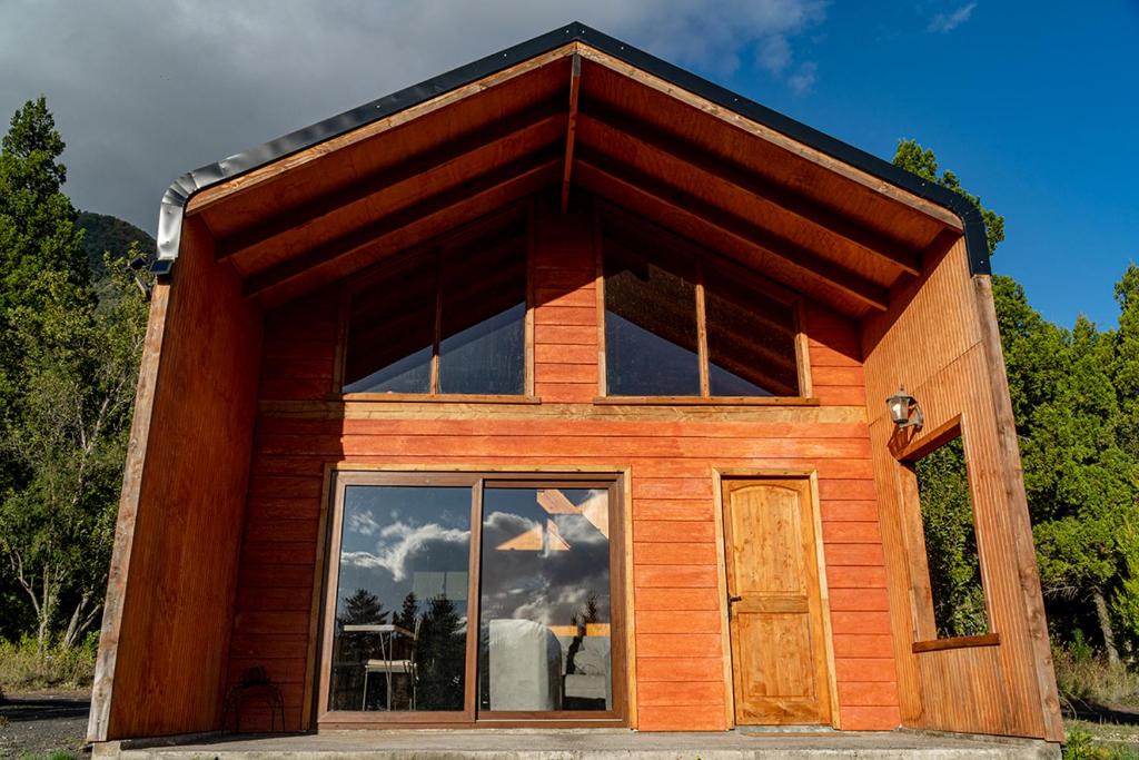 a small wooden house with a large window at Cabañas Origen Bosque y Río in Melipeuco