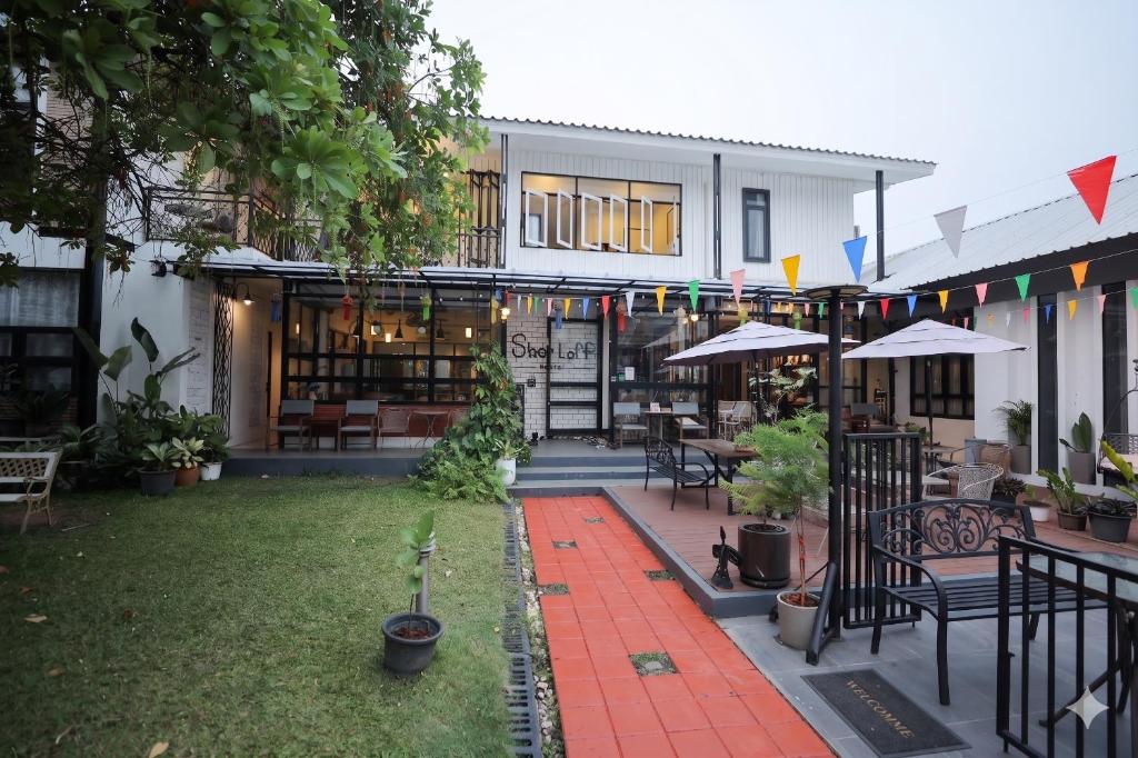 an outdoor patio with tables and chairs and a building at Sherloft Home & Hostel in Chiang Mai
