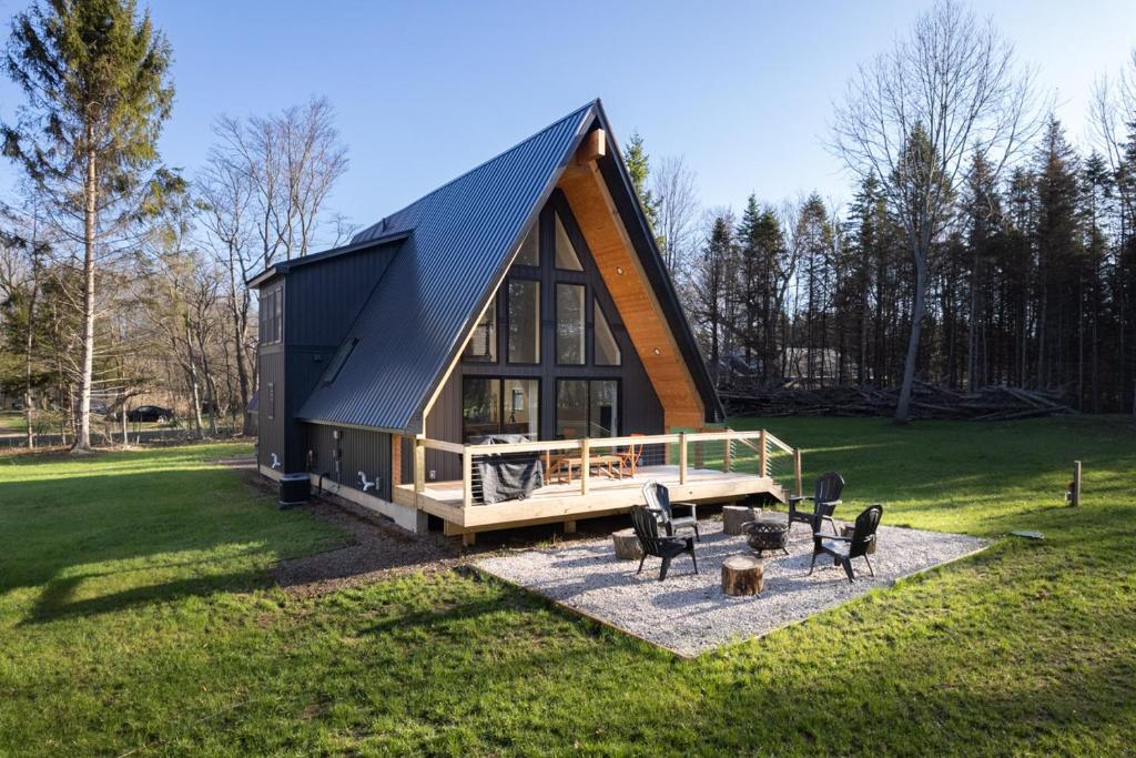 a house with a black roof on a green field at Secluded Architectural A-Frame w/ Soaring Windows & Fire Pit in South Haven