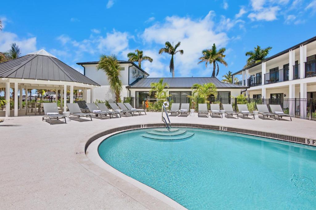 a swimming pool with lounge chairs and a building at Tropic Isle At Anna Maria Island Inn in Bradenton Beach