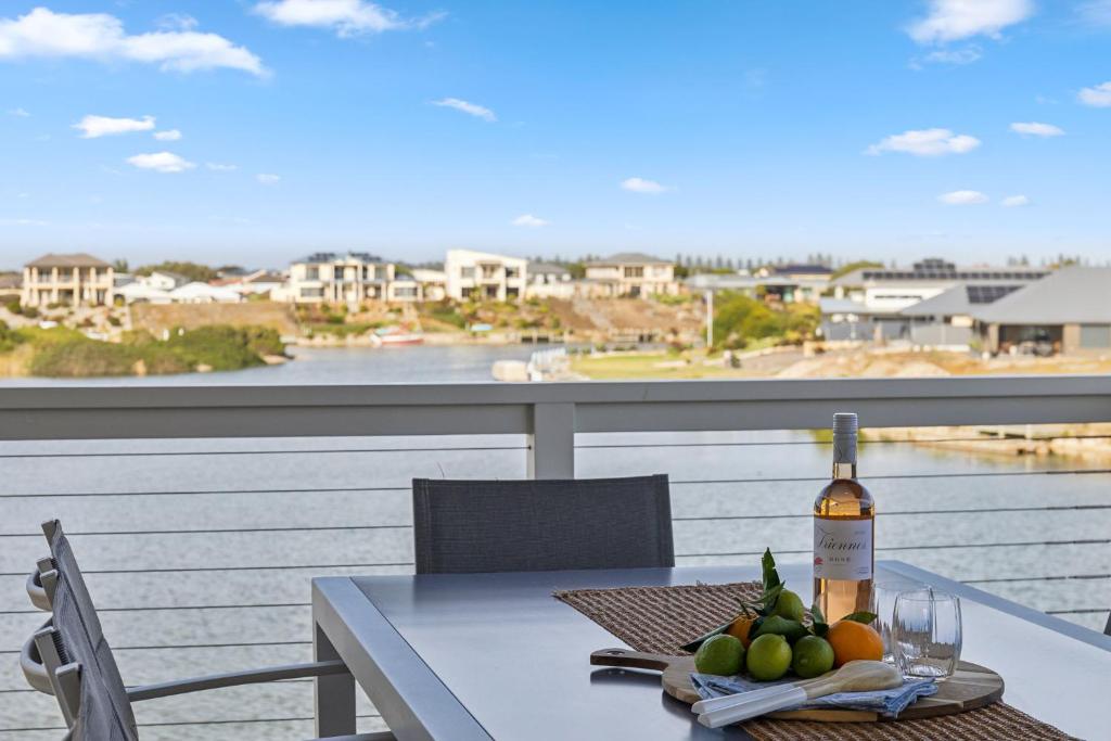 a table with a bottle of wine and fruit on a balcony at Lagoon Views in Hindmarsh Island