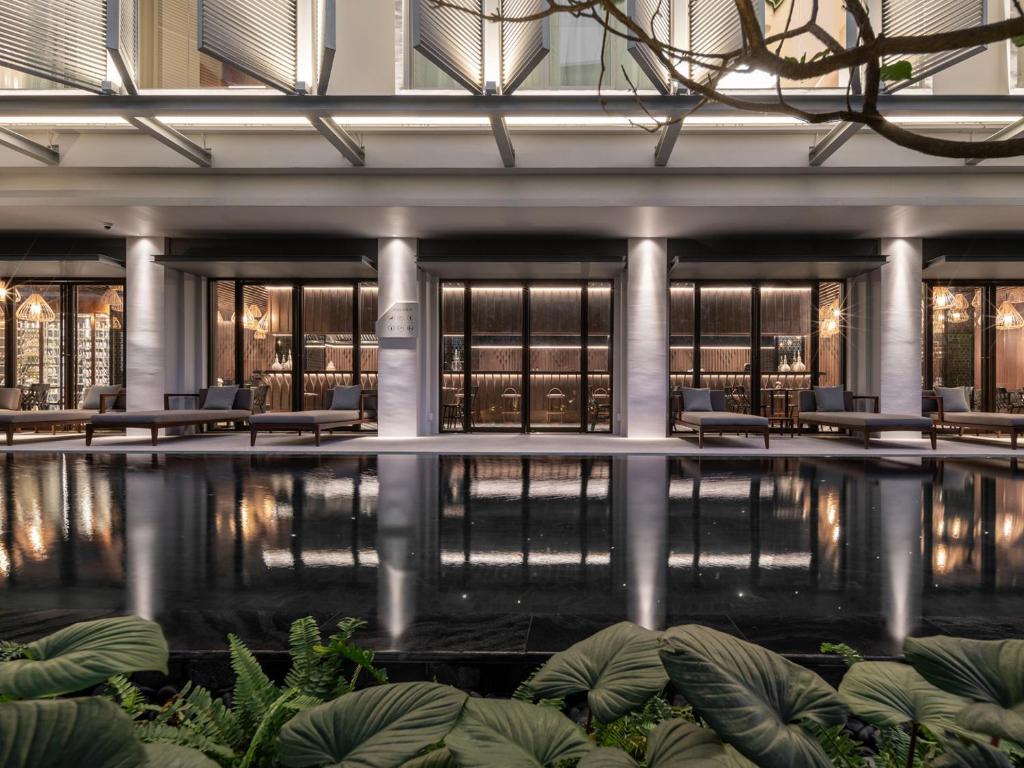 A reflective indoor-style pool courtyard framed by hotel seating and greenery.
