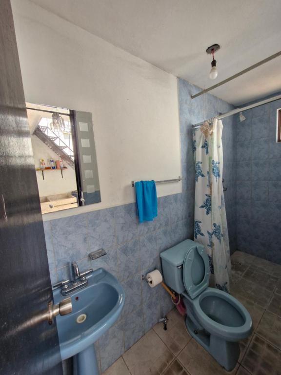 ein Badezimmer mit blauer Toilette und Waschbecken in der Unterkunft Casa Nicolette in Uruapan del Progreso