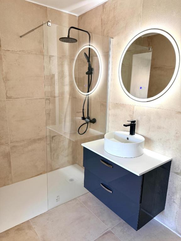 a bathroom with a sink and a shower with a mirror at Cosy Flat Cannes in Le Cannet