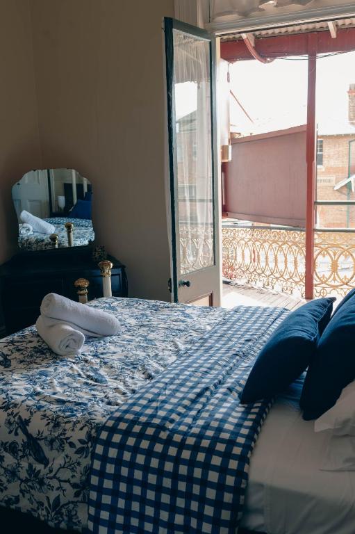 a bedroom with a bed with a blue and white blanket at The Great Central Hotel in Glen Innes