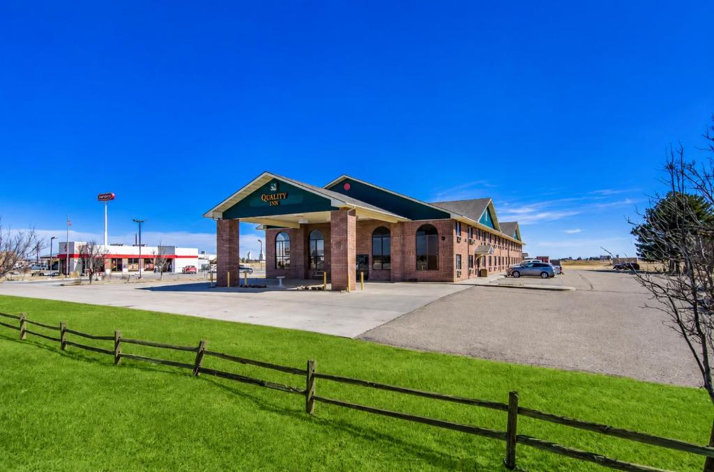 a building with a fence in front of a field at Quality Inn Goodland I-70 in Goodland