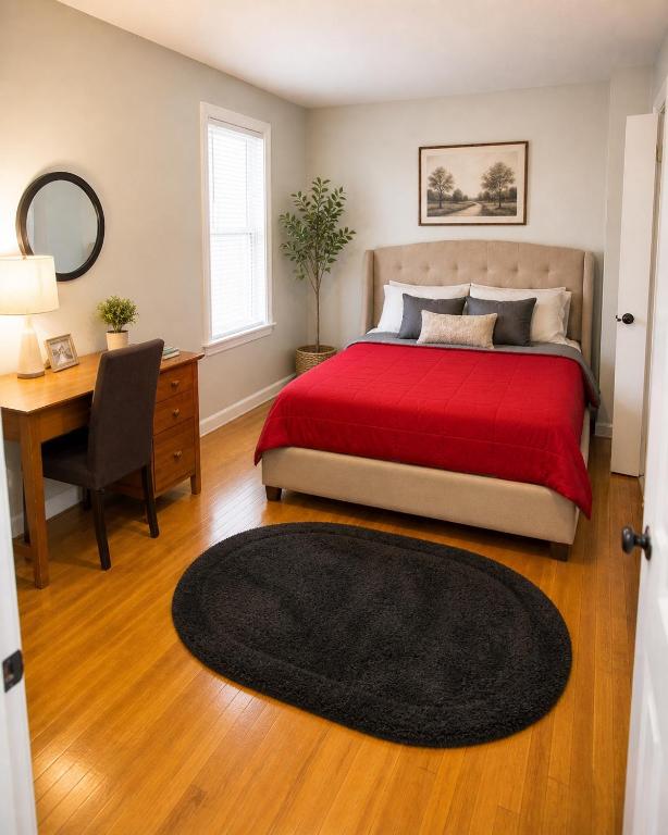 a bedroom with a bed with a red blanket and a desk at Fall River Stay Urban Haven Entire Suites Cozy 4BR in Fall River