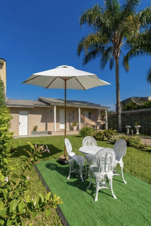 a table and chairs with an umbrella in a yard at Pousada Serra Farroupilha in Farroupilha