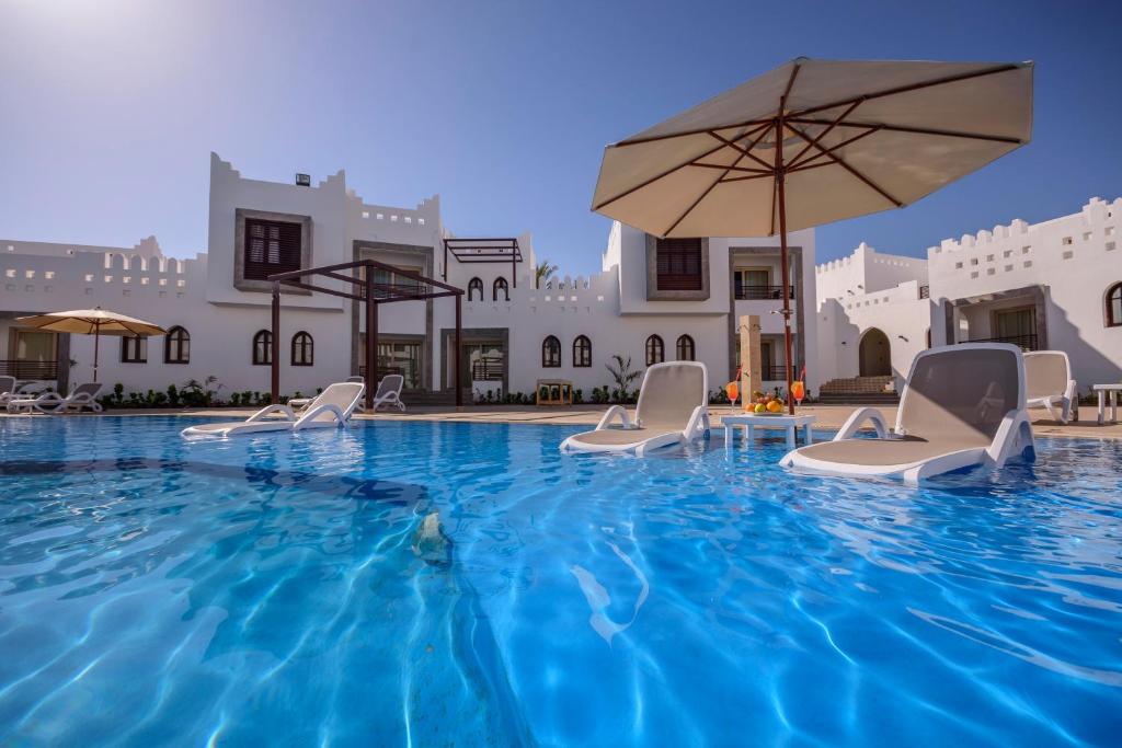 a pool at a hotel with chairs and an umbrella at Mazar Resort & Spa in Sharm El Sheikh