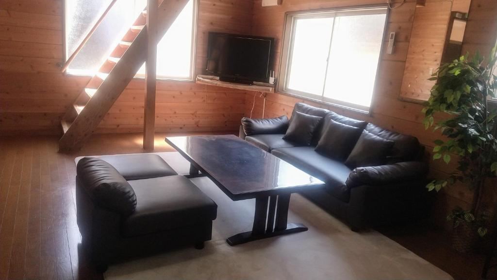 a living room with two leather chairs and a table at のんびれっじひなぎくａ棟 in Anazawa