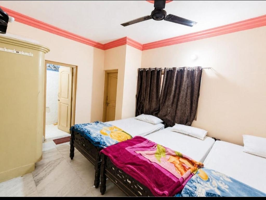 two beds in a room with a ceiling fan at Evergreen AC Bunglow in Dwarka