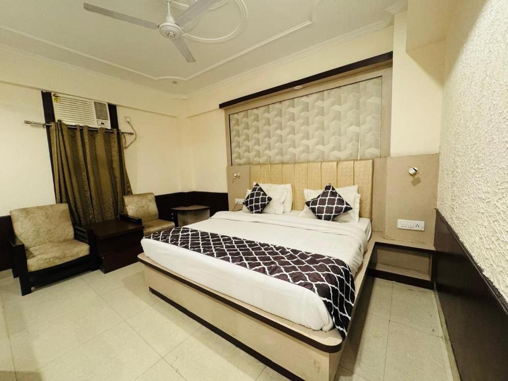 a bedroom with a large bed and a chair at Hotel Ganga Aatitheyam in Haridwār