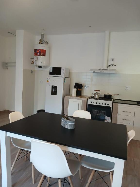 a kitchen with a black table and white chairs at Listo para vos in RSA