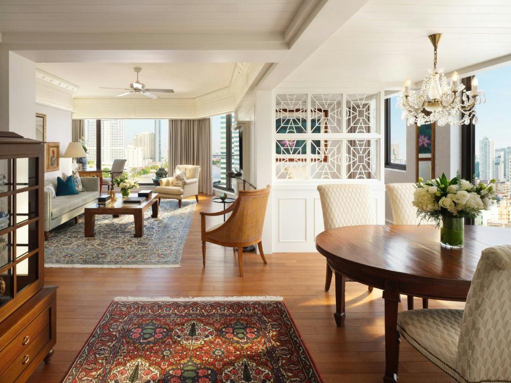 An elegant open-plan living and dining room with large windows and a chandelier.
