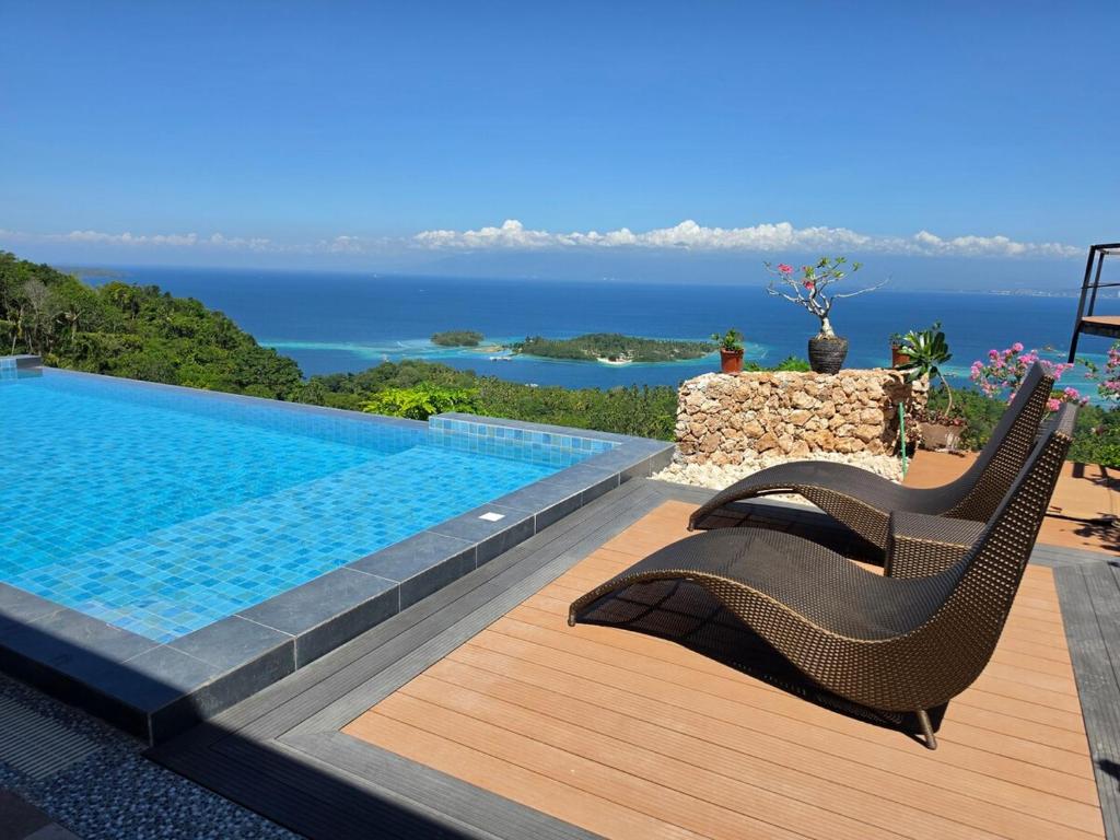 a swimming pool with two chairs and the ocean at Dream View Villa Samal in Samal