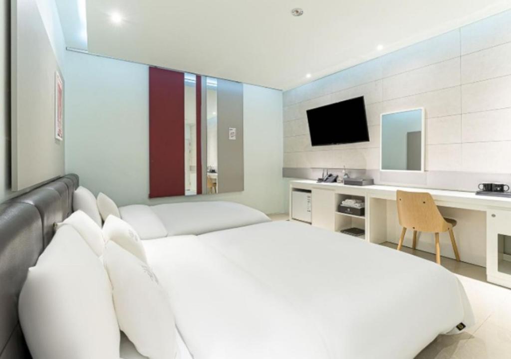 a bedroom with a bed and a desk with a television at Gimpo Pentastar Hotel in Gimpo