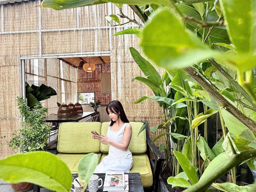 a woman sitting on a couch looking at her cell phone at Jazz Living - Tropical Apartment 5 minutes walk from landmark 81 in Ho Chi Minh City