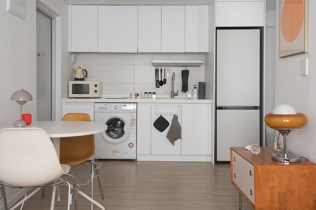 a kitchen with white cabinets and a table and chairs at 서울역 2분거리, 클레어맨션 201 in Samgong