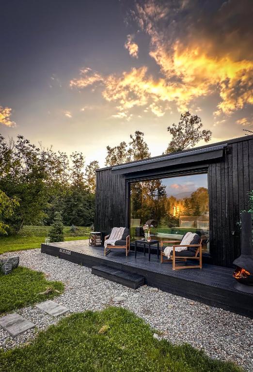 a small black cabin with two chairs and a table at Forest Chalet in Porumbacu de Sus