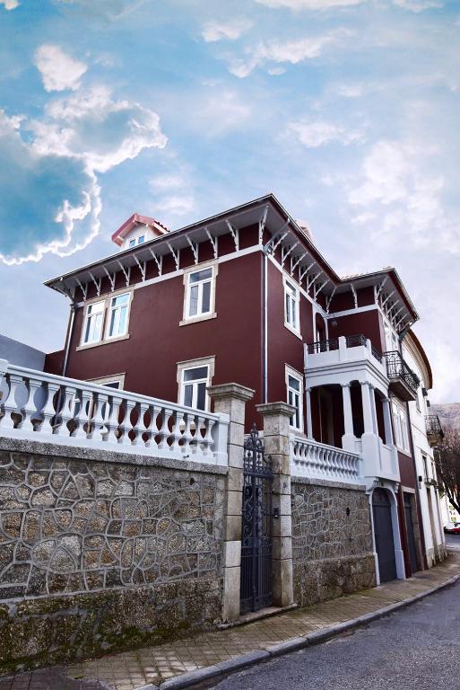 uma casa vermelha e branca com uma cerca de pedra em Casa com Historia na Covilh