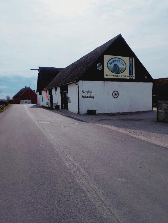 a white building with a black roof next to a road at Drottning Ödas Boende in Degerhamn